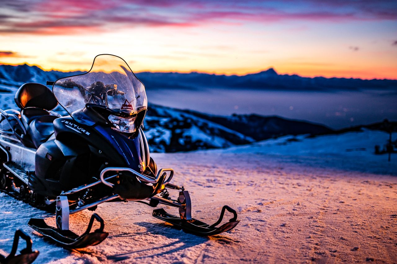 Home Snowmobile parked on snowy hillside at sunset in Prato Nevoso, Piemonte, creating a vibrant winter scene.